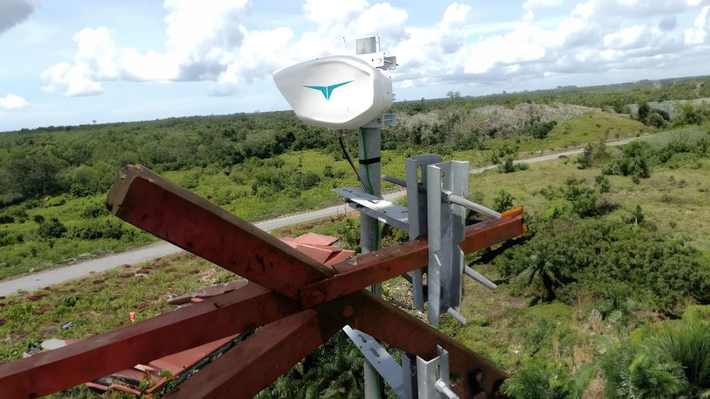A laser terminal on an exposed field mast under heavy cloud.